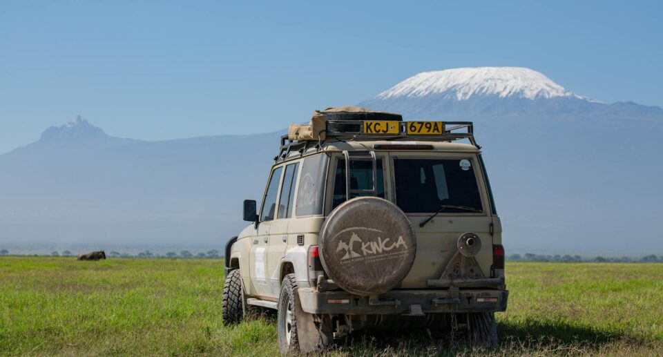 SUV auf Grasland mit Kilimanjaro im Hintergrund unter blauem Himmel