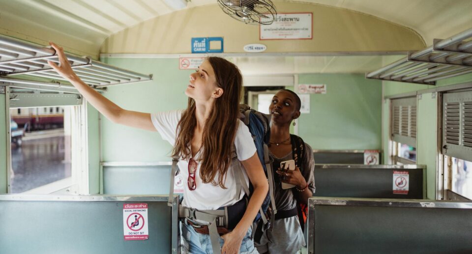 Zwei Rucksacktouristinnen verstauen ihr Gepäck in einem Zugabteil auf ihrer Asiareise