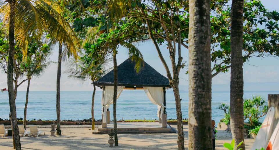 Tropischer Pavillon mit Palmen am Strand von Bali, mit Blick auf das ruhige Meer