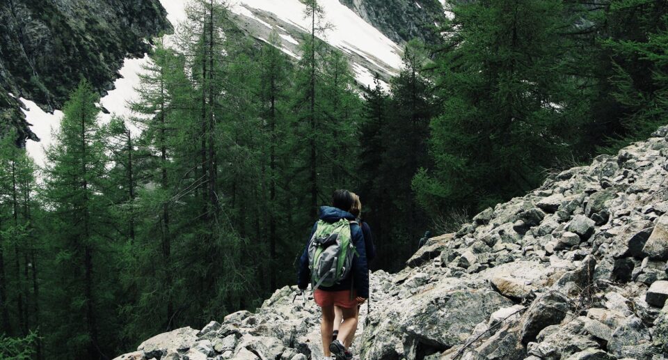 Rucksacktourist wandert über felsiges Gelände in Champoléon mit schneebedeckten Alpengipfeln im Hintergrund