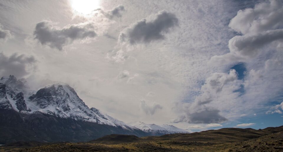 Schneebedeckte Torres del Paine unter Sonnenschein und Wolkenhimmel in Patagonien