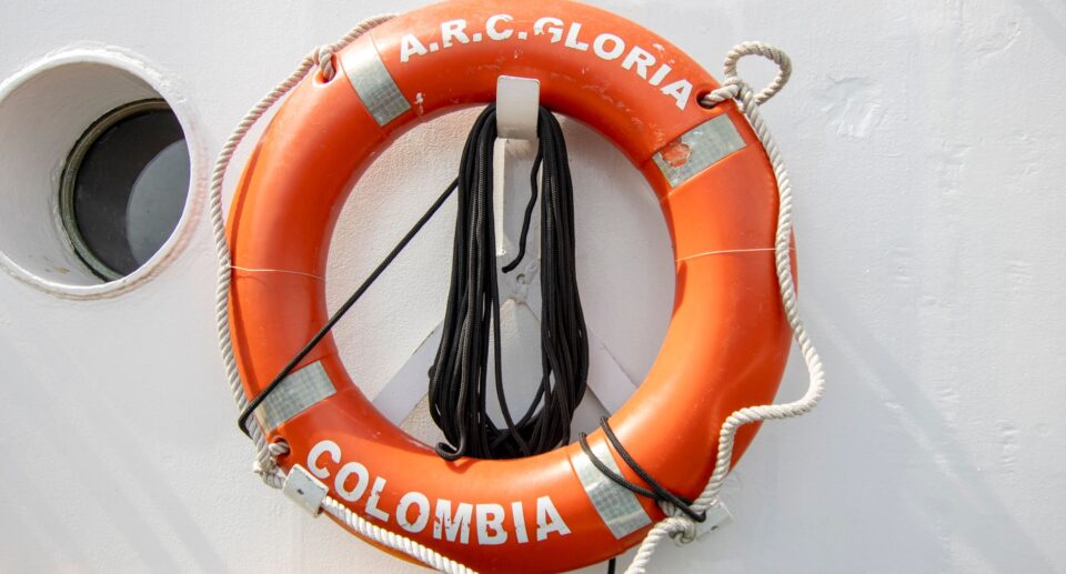 Orangene Rettungsboje mit Aufschrift A.R.C. Gloria an einem Schiff in Kolumbien