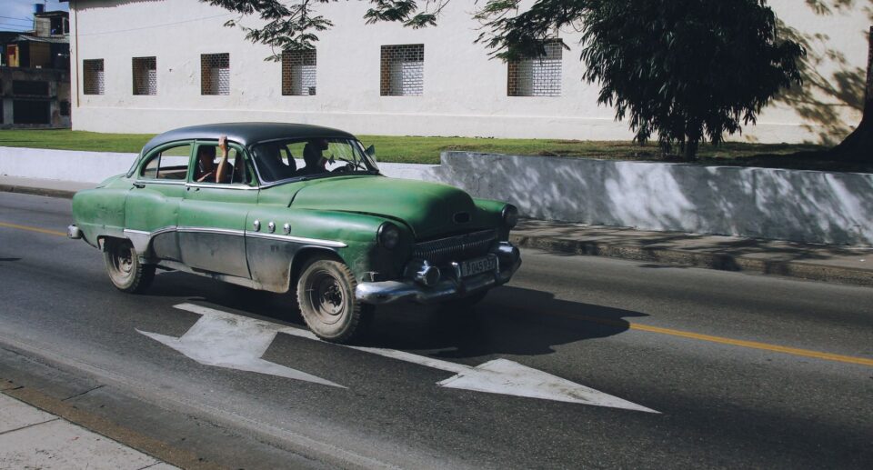 Klassischer grüner Oldtimer auf Kubas Stadtstraße unter blauem Himmel