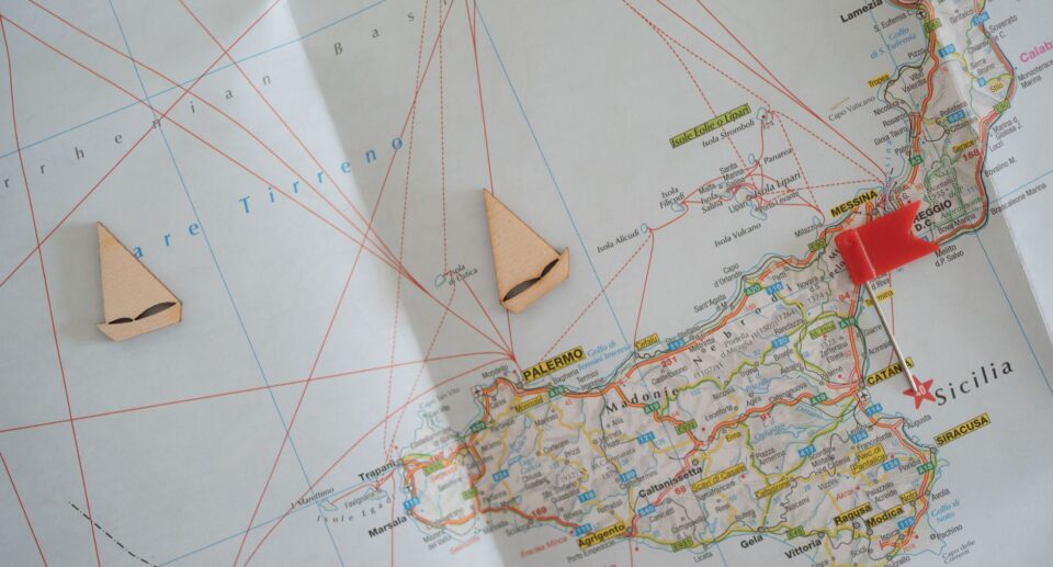 Sizilien-Karte mit Holzboot-Markierungen und roter Stecknadel zur Routenplanung