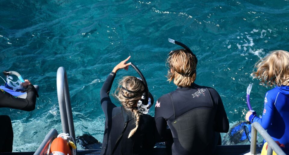 Gruppe von Schnorchlern bereitet sich auf ihr Barrier Reef Snorkel Abenteuer in kristallklarem australischen Wasser vor